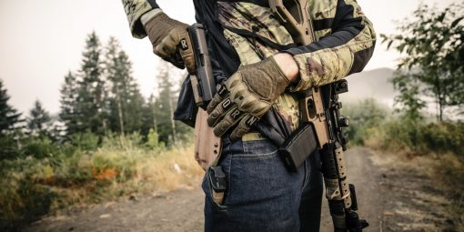 Man in Wartorn gloves holding gun
